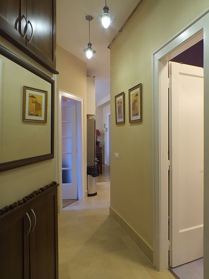 Előszoba a bejárati ajtóból. A bal oldali ferde falba épített szekrények közötti tükör túloldalán a fürdőszoba falfülkéi találhatók.